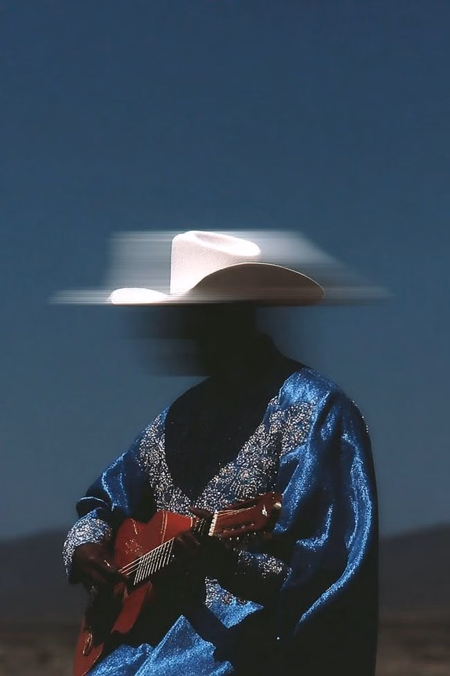 A figure under a motion-blurred white hat, face lost to the blur, holding a red instrument steady