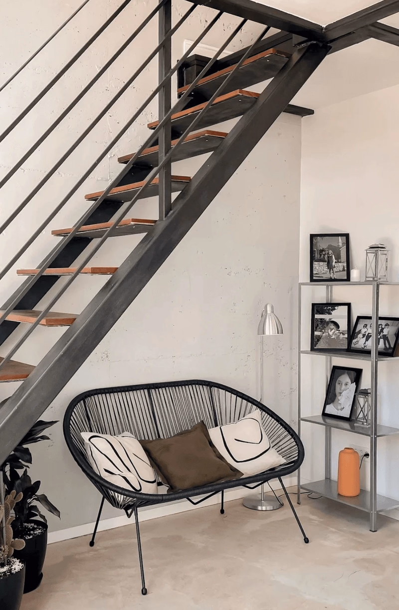The open steel stair to the mezzanine, with the lounge set underneath it