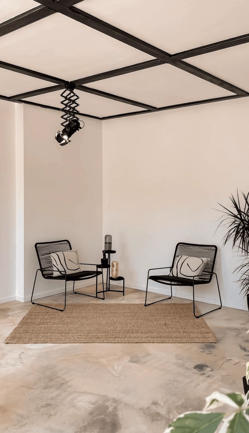 The main floor: poured concrete, white walls, a black ceiling grid carrying a single theatre spot